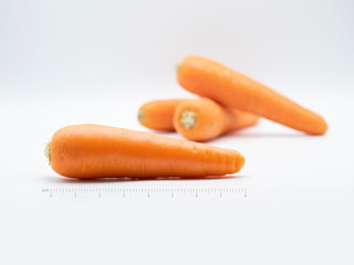 Carrot from market on white background with ruler scale. It is an ingredient for savoury, dessert, beverage. Salad, soup, cake, smoothie and many dish that can made by carrot and good for health.