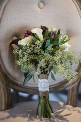 wedding bouquet with white lilies and greenery on chair