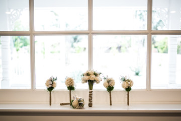 multiple small wedding bouquets with white roses on a window ledge