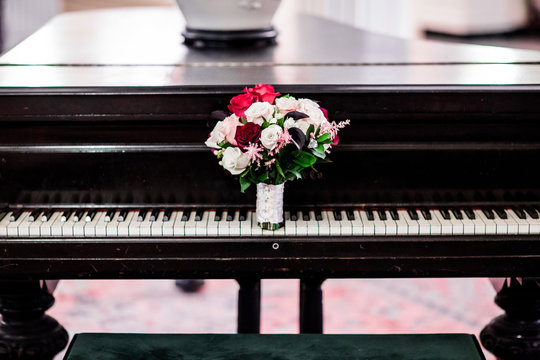 wedding bouquet with red and pink flowers leaning on vintage piano