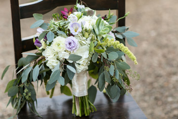 wedding bouquet with lots of greenery on chair