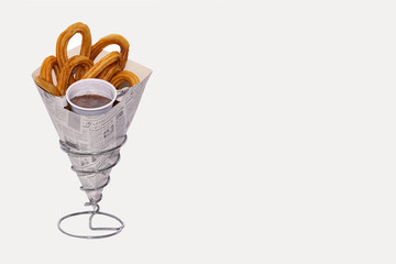 Churros with hot chocolate cone presented on a metal stand. Off-white background with copy space....