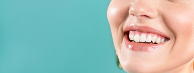 Lachende vrouw mond met grote tanden op een blauwe achtergrond. Gezonde witte tanden. Brede glimlach. Mondverzorging.
