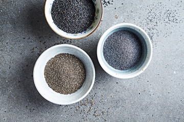 Blue poppy seeds, black sesame and black chia in ceramic bowls. Healthy food ingredients. Flat lay