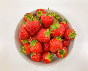 Plump ripe fresh strawberries in a white bowl on a plain white background.