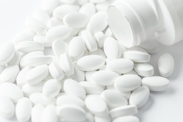 Fototapeta na wymiar white Pills, tablets, medical drugs or food supplement spilling out of bottle
