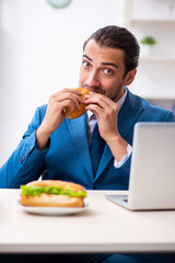 Young male employee having breakfast at workplace