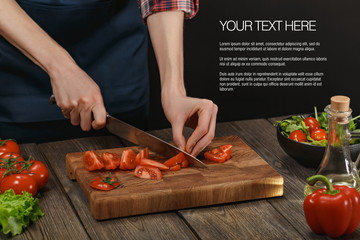 Woman cooking fresh healthy salad. Female hands cutting vegetables on board on wooden table with sample text.