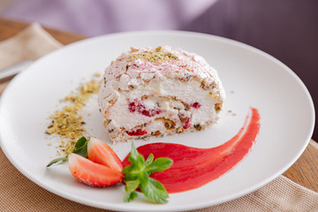 beautiful tasty green vegan dessert pistachio strawberry rolls on a wooden table in the interior.