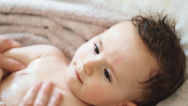Close up of nice caucasian newborn baby on the bed and sucking a pacifier