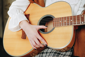 Hands of a young girl with a guitar closeup