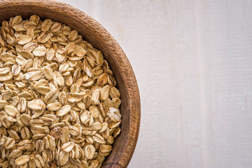 Oatmeal in wooden bowl on white background. Top view. Copy space.