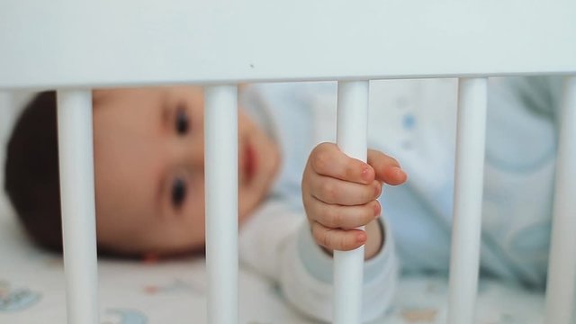 Close up of nice caucasian newborn baby on the bed and sucking a pacifier