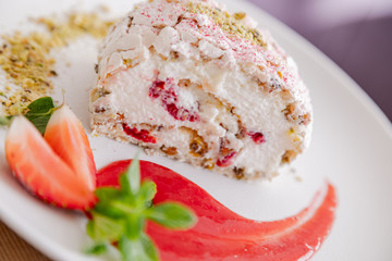 beautiful tasty green vegan dessert pistachio strawberry rolls on a wooden table in the interior.