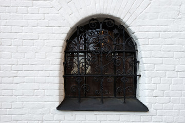Window in an old brick house protected by forged bars