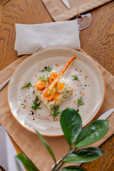 Traditional Russian salad Olivier. Salad is decorated with salmon and quail egg. Against the background of a wooden served table