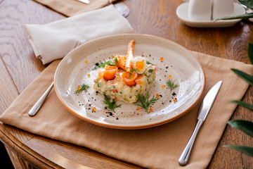 Traditional Russian salad Olivier. Salad is decorated with salmon and quail egg. Against the background of a wooden served table