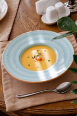 cream of salmon soup, in a bright blue plate, decorated with pieces of salmon, microgreens and butter. On the background of a wooden table.