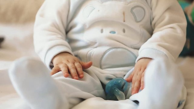 Close up of nice caucasian newborn baby on the bed and sucking a pacifier