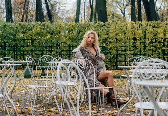 Young blond girl sitting at table in public park - 349900241