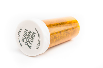 Close up of medical marijuana in yellow pill bottle on white background