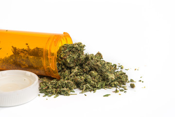 Close up of medical marijuana in yellow pill bottle on white background