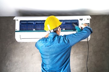 Technician man repairing ,cleaning and maintenance Air conditioner on the wall in bedroom or office room.On site home service,Business ,Industrial concept.