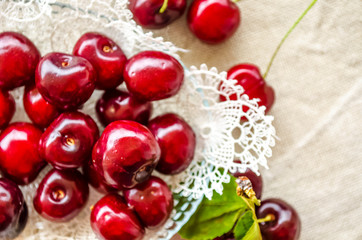 Beautiful bright red berries of sweet cherry. Close-up. Juicy sweet cherry berries in ceramic bowl on brown wooden table. Linen cloth. Vegetarianism, raw food concept. Fruit vitamin background.