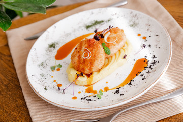 mashed potatoes with cutlet, on a beautiful white plate. The dish is decorated with micro-greens. Against the background of a wooden table in the interior.