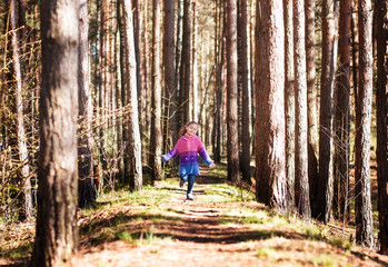 Obraz premium little girl runs through the sunny forest