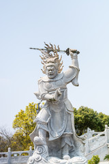 Fototapeta na wymiar Statue of the Viruḍhaka Heavenly King in front of Golden statue of bodhisattva guanyin Mount Luojia, Zhoushan, Zhejiang, the place where Bodhisattva Guanyin practiced Buddhism