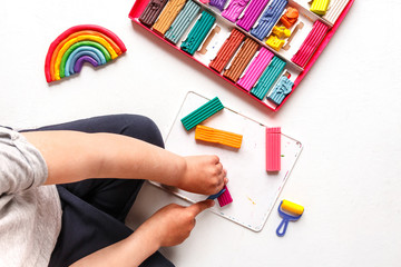 Toddler boy sculpting colored rainbow from children's play clay plasticine  ome. Homework for...