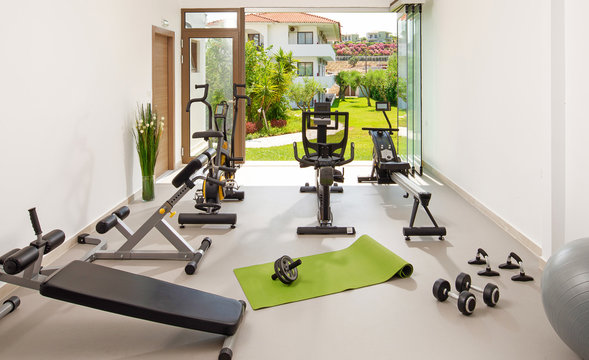 Modern concept of green nature eco style gym. Front view of stylish training room interior in hotel, apartment, house with open air garden window