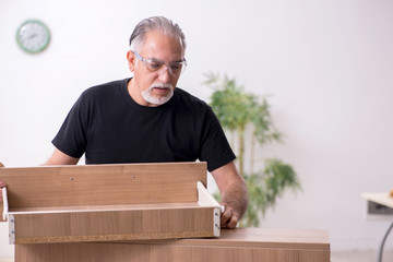 Old male carpenter working indoors
