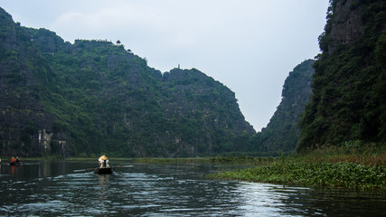Fototapeta na wymiar Vietnamese Boat owner rowing her Boat with legs at Ninh Binh, Vietnam, Asia