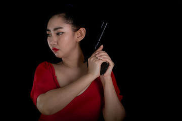 Fototapeta premium Portrait beautiful Asia woman wearing a rad dress one hand holding pistol gun 11mm. at the black background, Young sexy girl long hair with a handgun, Pretty women stand with a guns