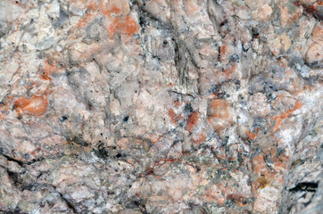 Pink granite texture with orange spots and black stains.