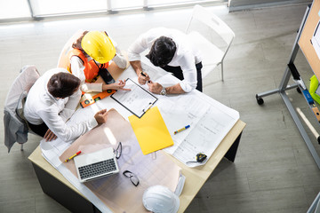 Three architects in the office and discussing design project on the table.
