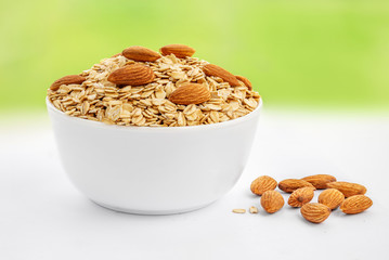 Oatmeal breakfast with almond nuts in bowl on a spring blurry  background. Healthy food concept