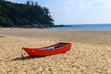 Tropical landscape. Red wooden boat on a sandy beach.