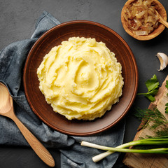 Mashed potatoes, boiled puree in a brown plate on a black slate background. Top view. Flat lay.