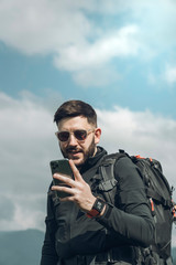 Young man using the smartphone while is walking in the nature