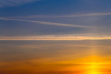 magical sunset, beautiful light from the sun, the trace of an airplane in the sky, colored lines in the sky, Cirrus clouds