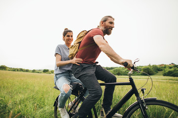 Romantic couple is riding a bike together in nature