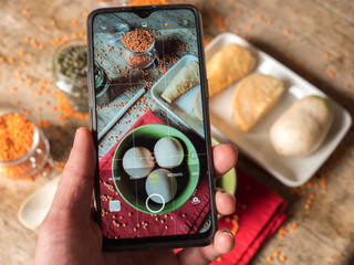 Taking a photo of orange lentils eggs, sunflowers seeds and other vegetables with a smartphone