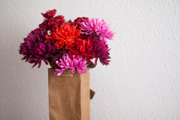 Ramo de flores rosas, rojas y magenta en una bolsa de cartón para regalar el día de la madre, en san Valentón. cumpleaños, aniversarios y otras celebraciones