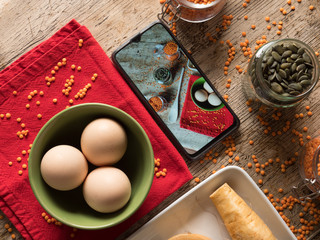 Orange lentils eggs, sunflowers seeds and other vegetables with a smartphone picture.