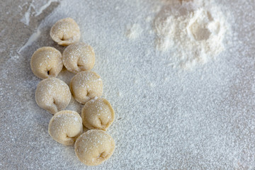 Homemade dumplings close-up.  Dumplings ears lie on a table sprinkled with flour