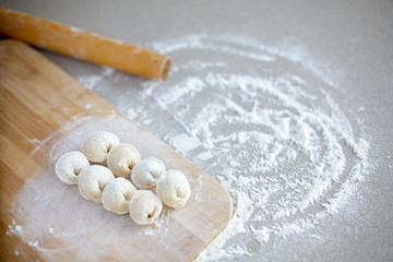 Fototapeta na wymiar Homemade dumplings close-up. Dumplings ears lie on a table sprinkled with flour