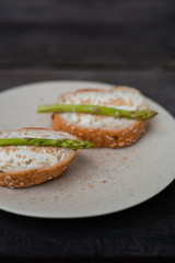 sandwich with asparagus curd cheese on a ceramic light plate on a wooden background